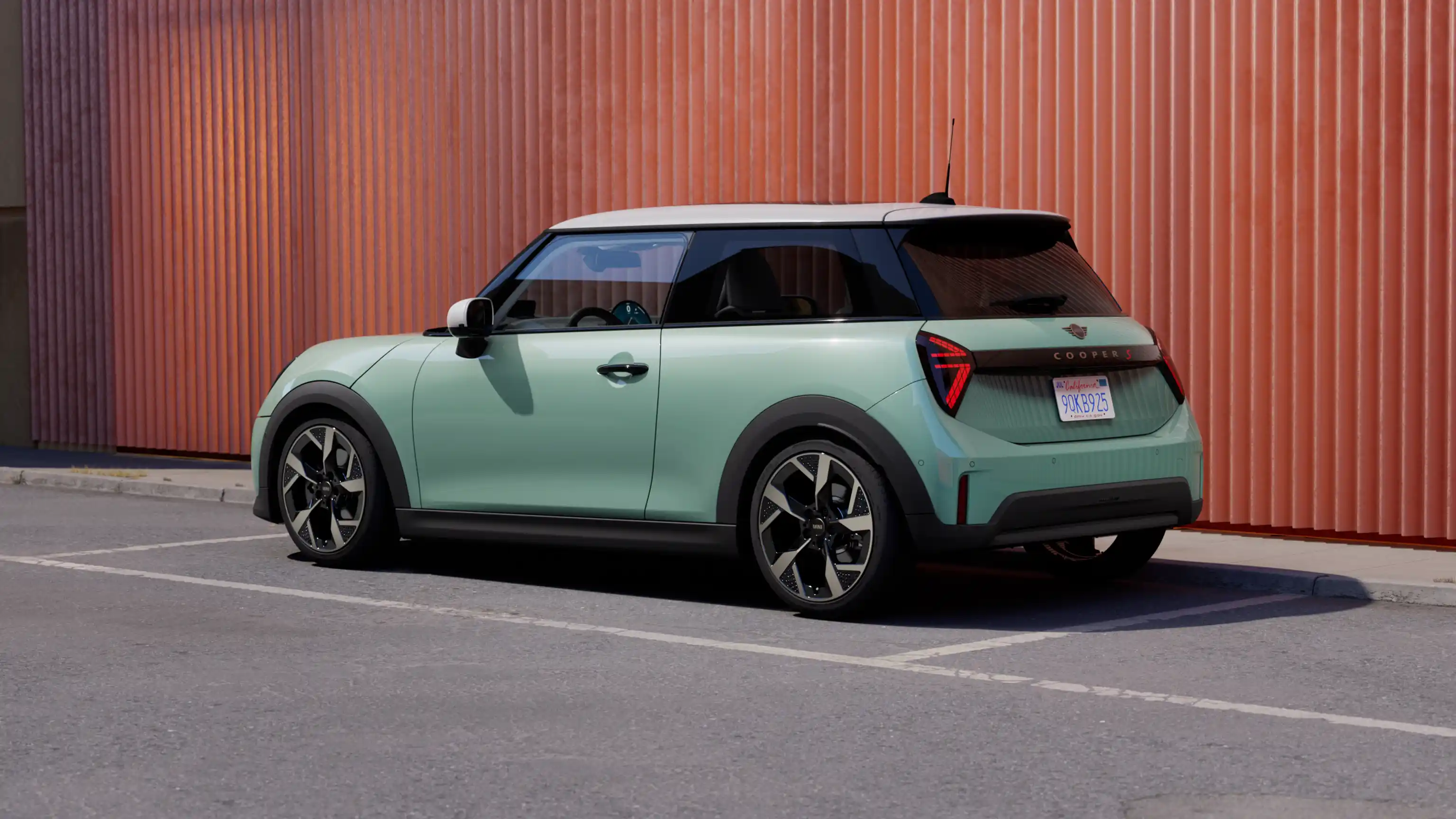 Prikaz zadnje leve strane MINI Cooper-a Ocean Wave zelene boje sa belim krovom prilikom parkiranja