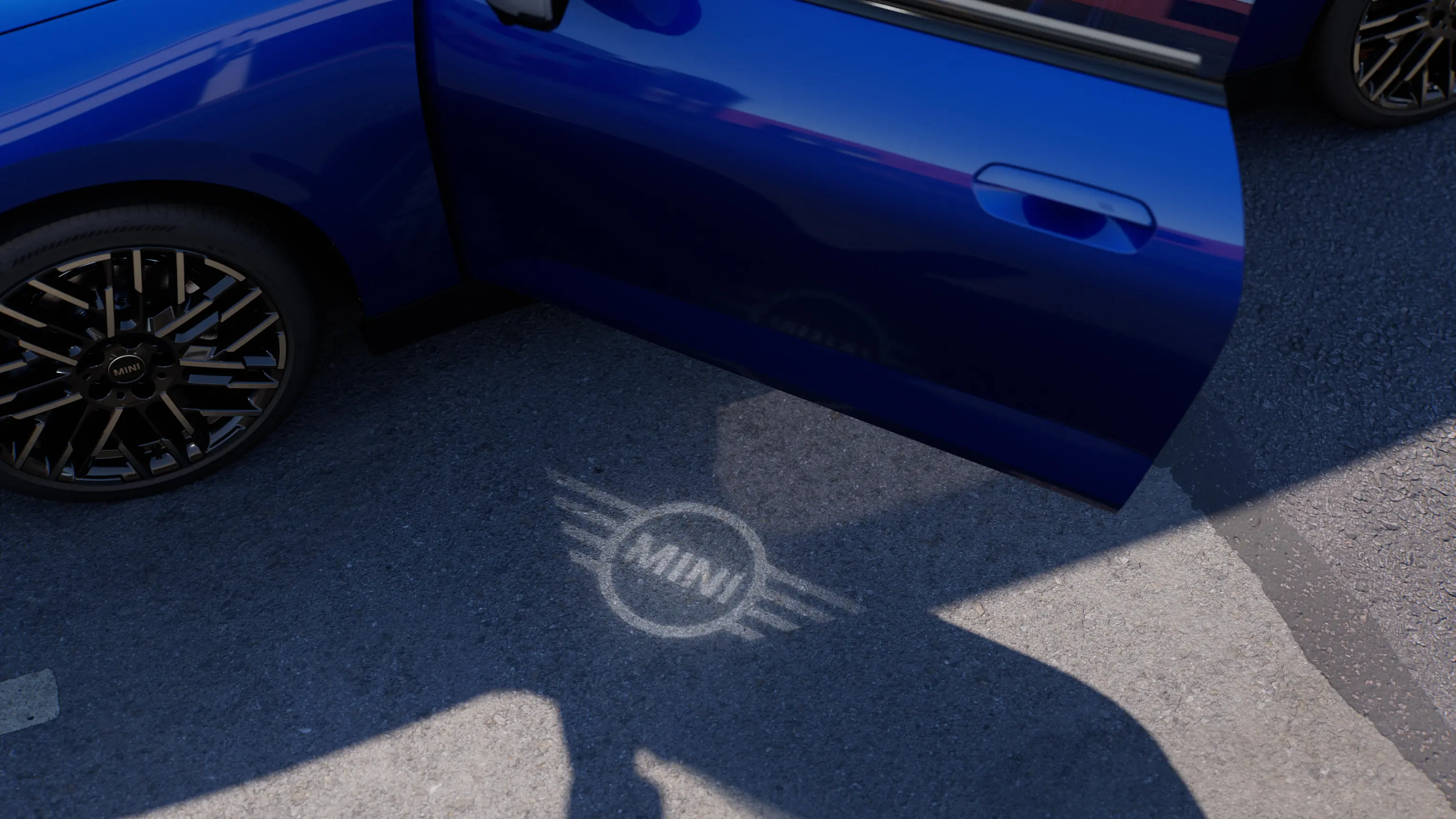 Spoljašnji prikaz potpuno električnog MINI Cooper-a sa otvorenim vratima i MINI svetlom dobrodošlice sa projekcijom logotipa na zemlji