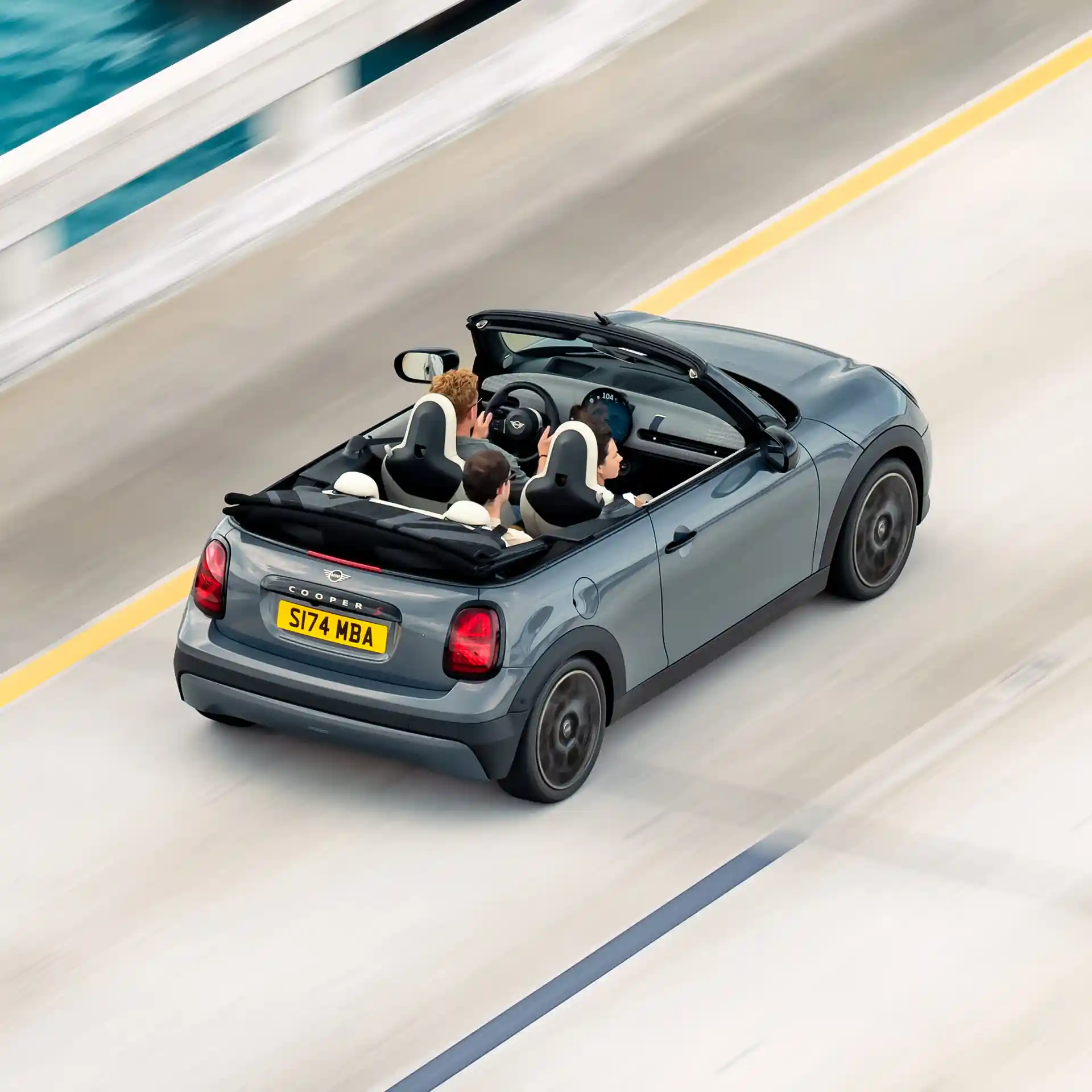 Prikaz zadnje strane MINI Cooper Kabriolet odozgo tokom vožnje ulicom