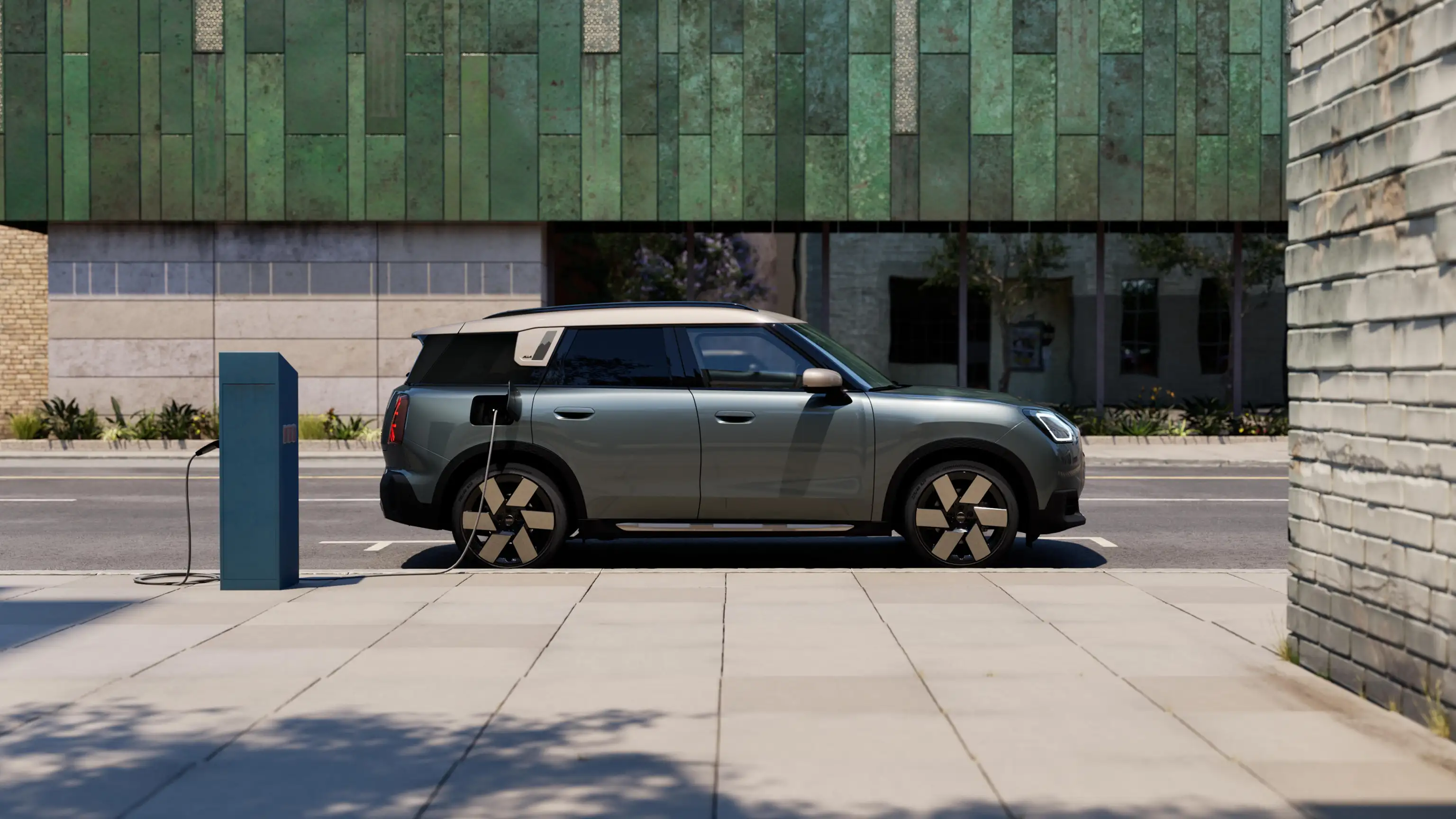 Bočni prikaz potpuno električnog MINI Countryman-a Smokey zelene boje sa Vibrant srebrnim krovom na ulici