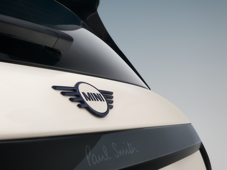Snimak izbliza zadnjeg amblema sa krilima na potpuno električnom MINI Cooper Paul Smith izdanju u boji Inspired White.