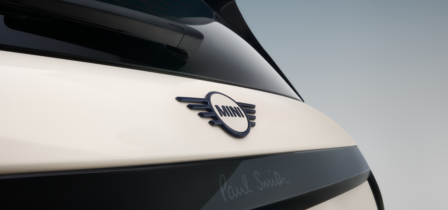 Snimak izbliza zadnjeg amblema sa krilima na potpuno električnom MINI Cooper Paul Smith izdanju u boji Inspired White.