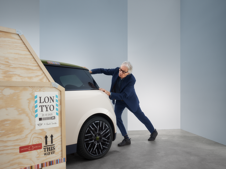Pogled otpozadi na potpuno električni MINI Cooper Paul Smith izdanje u boji Inspired White, dok Paul Smith stoji iza automobila.